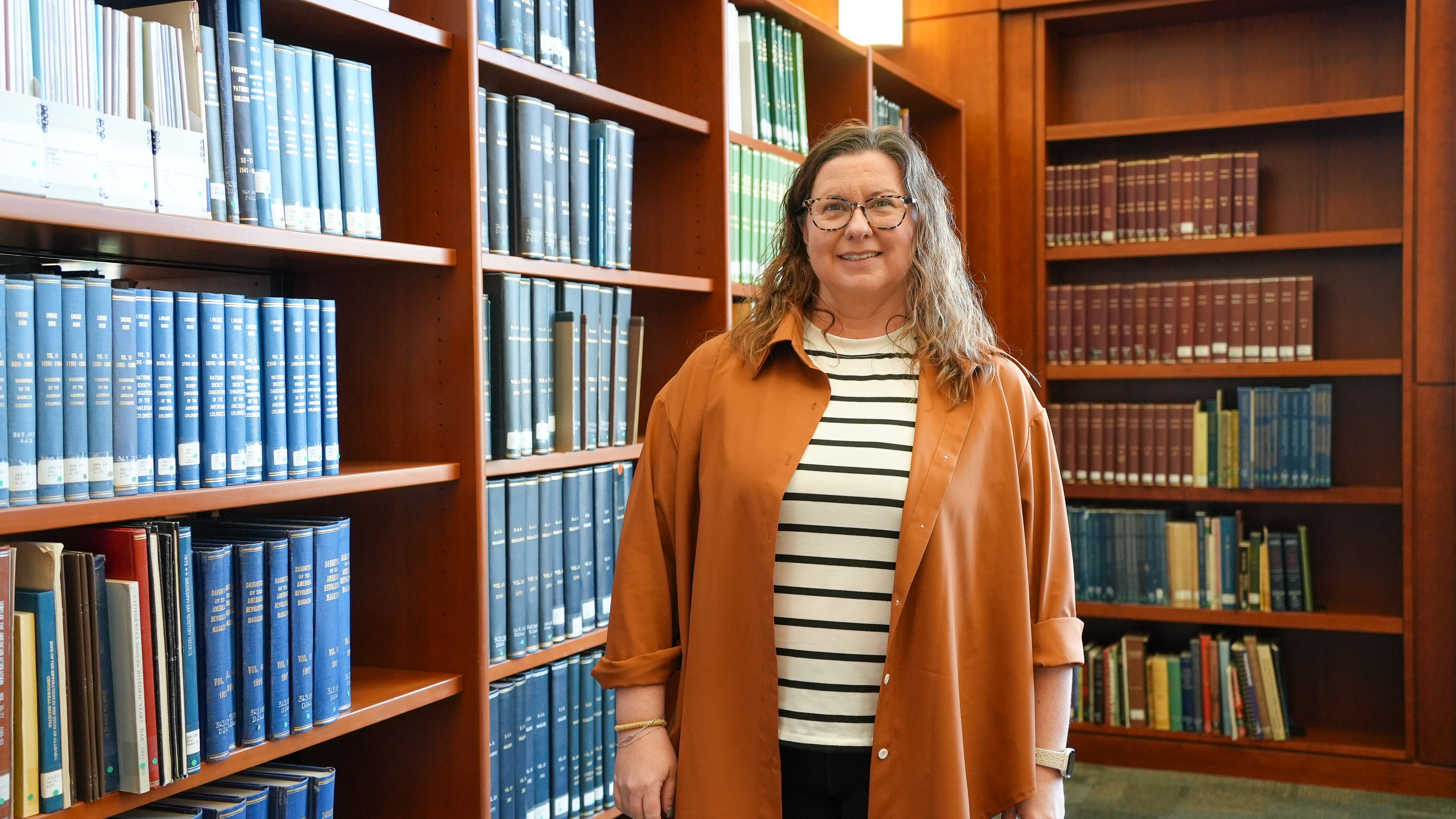 Photo of Andrea Scott standing next to research books.